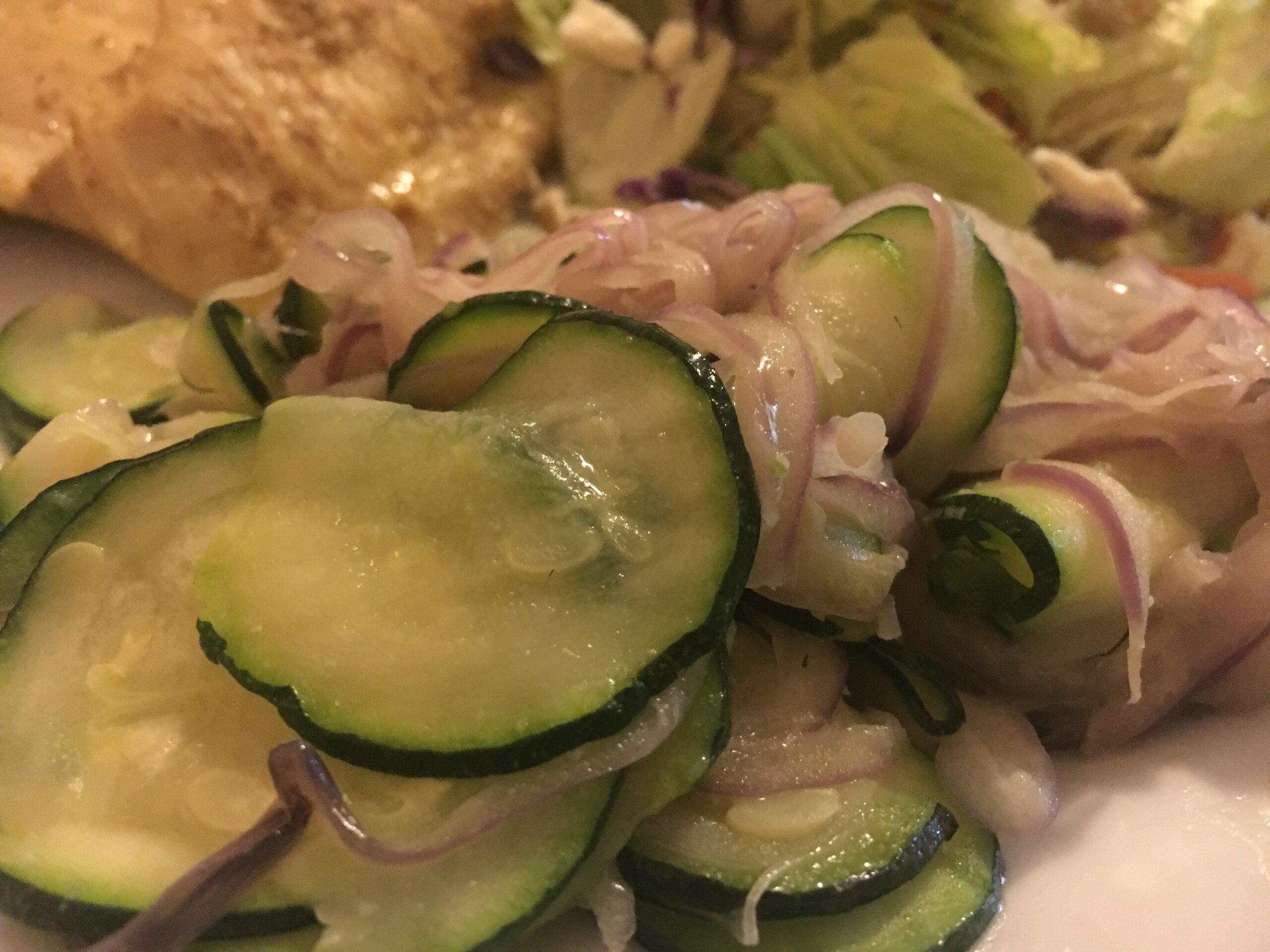 Sauteed Zucchini with red onions plated with a side salad and chicken breast