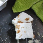 Creamy Key Lime Bars with a green dish towel in the back area of the image and a pan of the bars barely visible in the top left corner