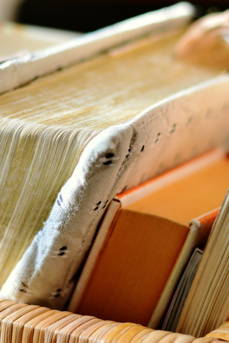 A basket full of closed books close up with the pages towards the viewer