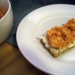 Tangy BBQ Chicken Salad plated on a white plate with a wasa cracker underneath the chicken salad and a blue cloth slightly visible between the plate and the white bowl almost out of the image in the upper left corner