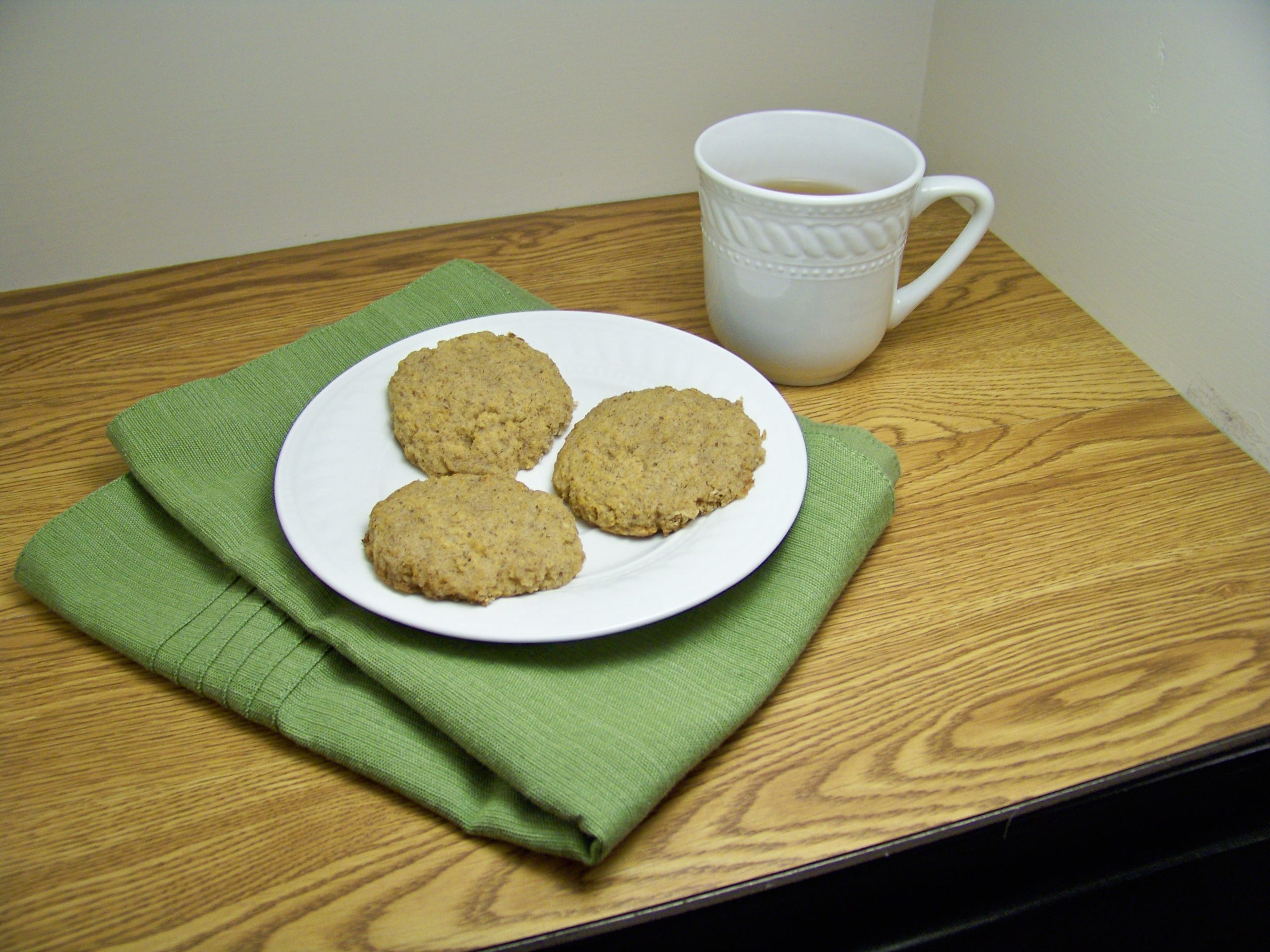 Chai Sugar cookies on a white plate with a green placemat folded underneath, a white mug of tea to the back right