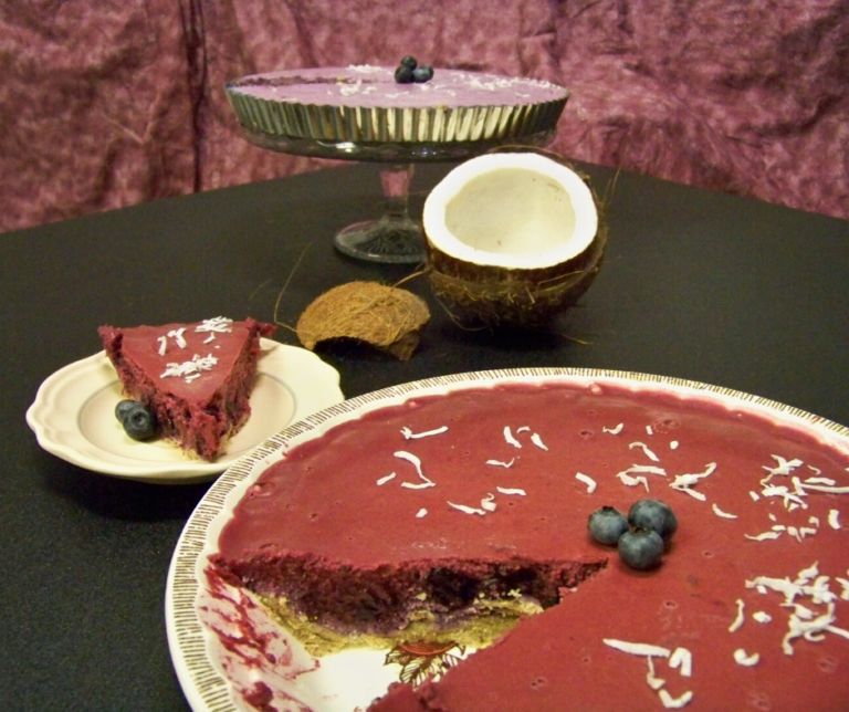Blueberry "Cream" Pie, one version sliced in the front with an open coconut between it and a short cake stand holding the second version of the pie in a tart pan