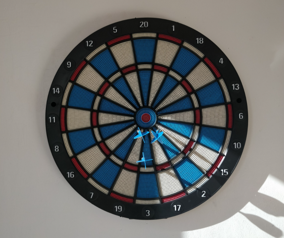 Blue and white target with three darts missing the bullseye