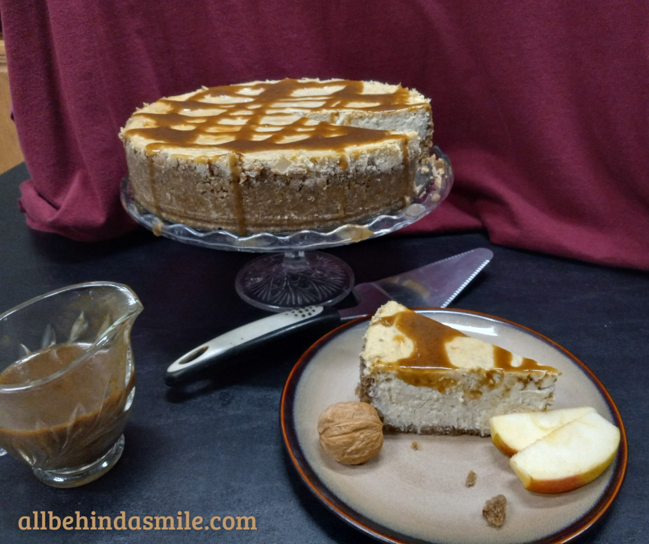 Autumn Apple Cheesecake on a platter with a slice on a plate and a server between