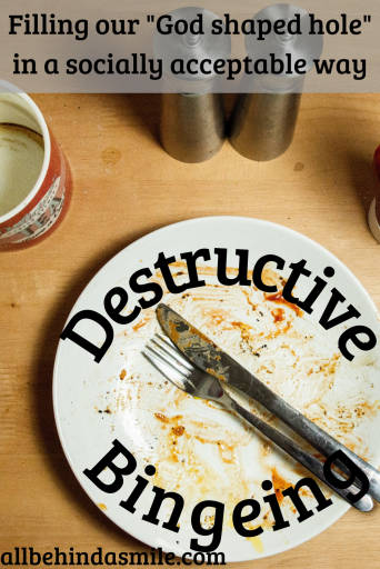 A dirty white plate with utensils on a wood tabletop with an empty coffee mug and salt and pepper shakers and the words "filling our God shaped hole in a socially acceptable way: Destructive Bingeing"