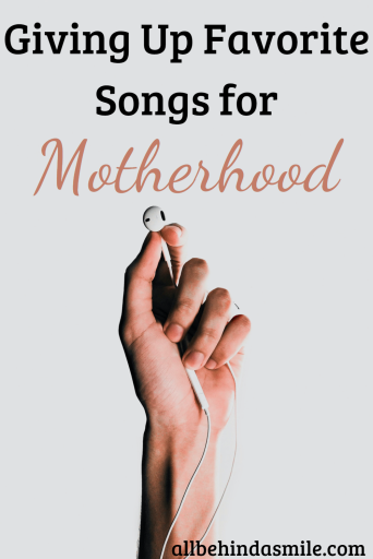 A hand holding a pair of wired earbuds with the text Giving Up Favorite Songs for Motherhood