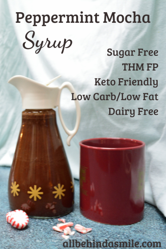 An antique syrup bottle full of peppermint mocha syrup beside a reddish coffee mug with the text sugar free, THM FP, keto friendly, low carb/low fat, dairy free