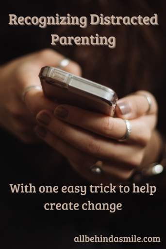Person's hands holding a cell phone over a dark background with the text recognizing distracted parenting with one easy trick to help create change